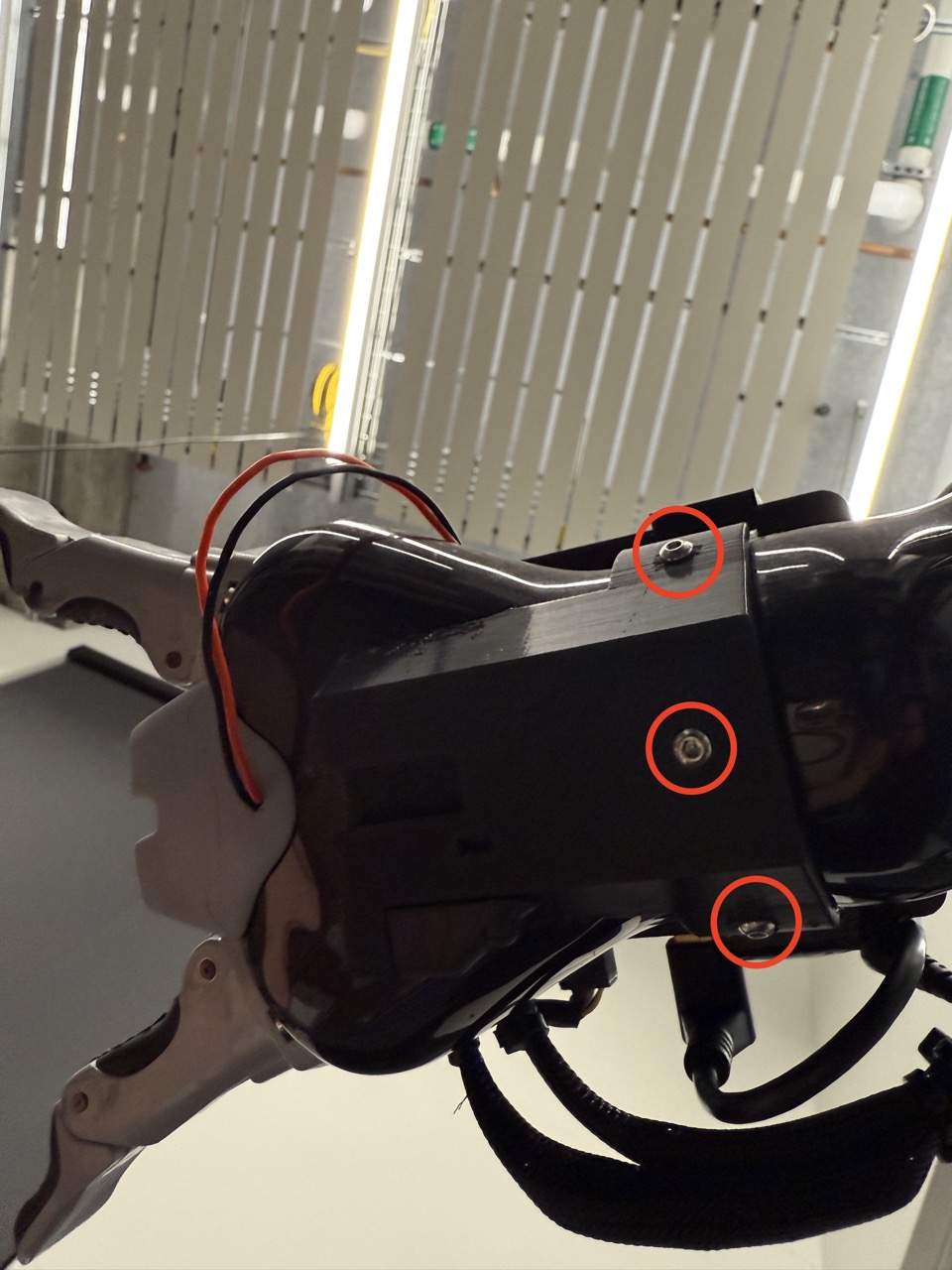 
                    A view from the underside of the robot arm, showing the arm mount
                    with the three screws circled in red.
                    