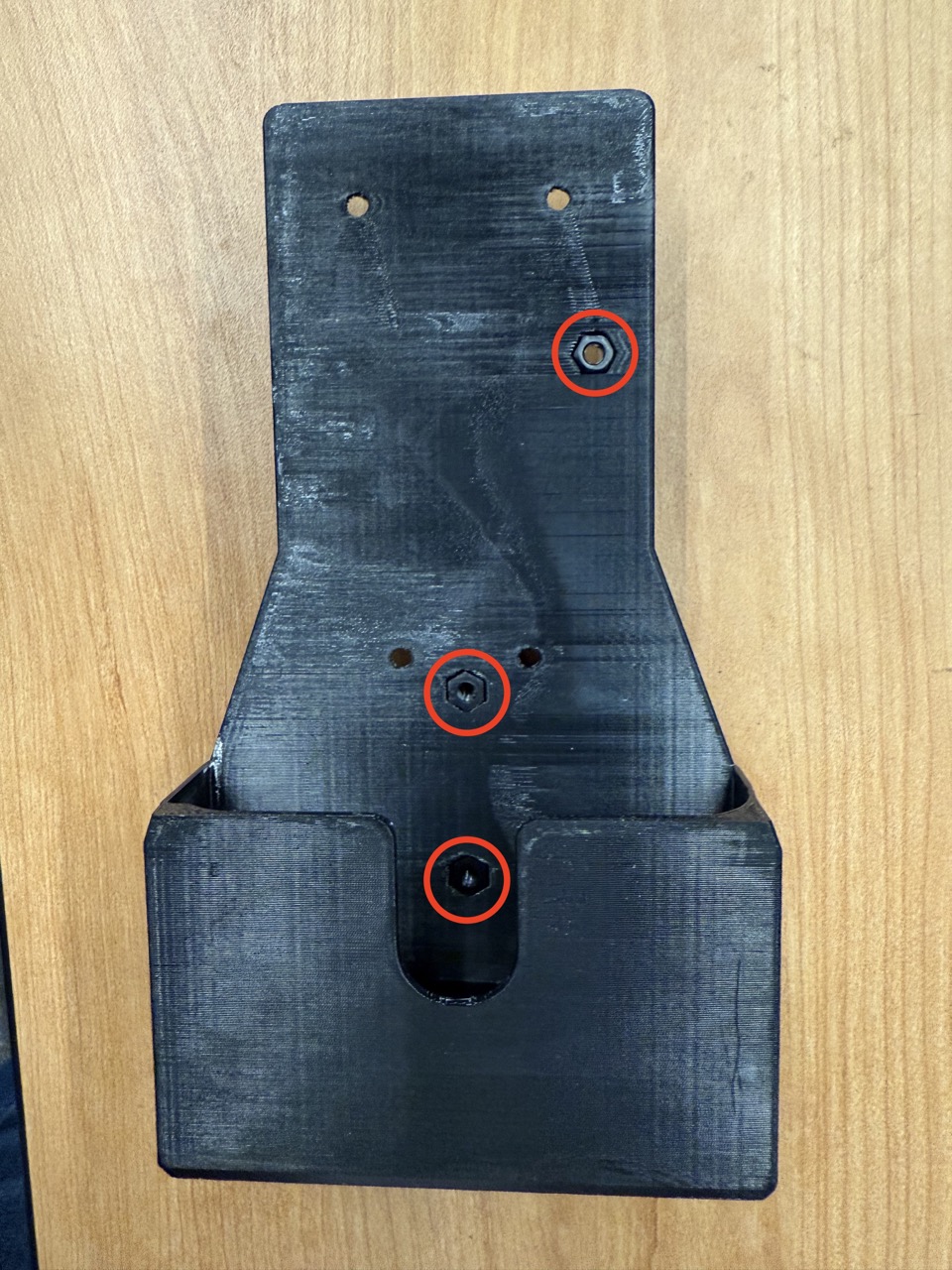 
                    This figure shows a photo of the inside of the wireless F/T mount,
                    with three nuts inserted into the hexagonal slots and circled in red.
                    