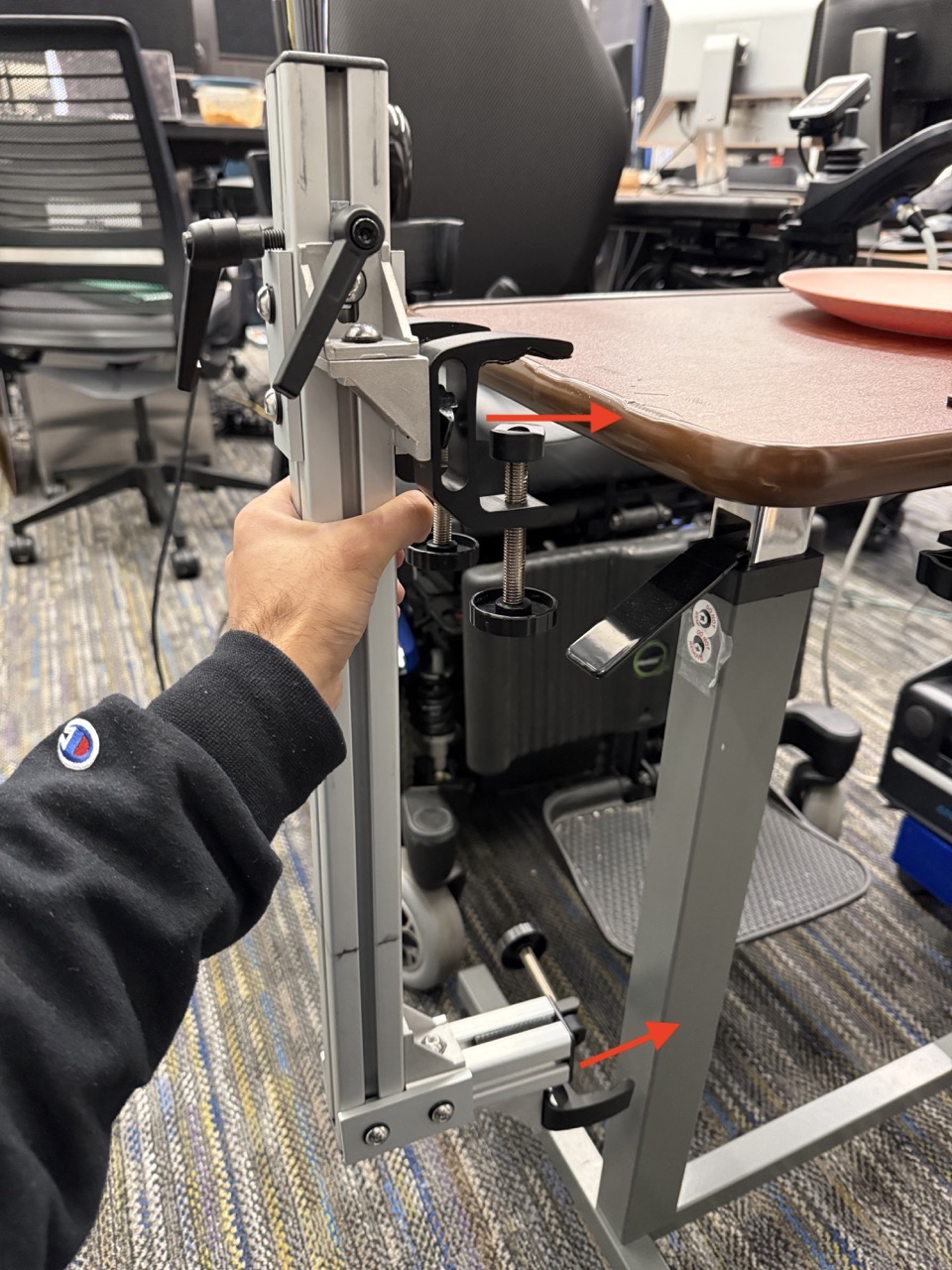 
                    The hospital table mount about to be clamped onto the hospital table,
                    with arrows indicating where the clamps join.
                    